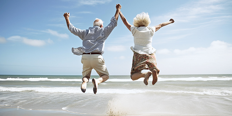 Image of couple jumping for joy at the beach.